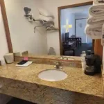 Bathroom vanity with granite countertop, sink, towels, and coffee maker at The Dutton Inn | Branson Mo