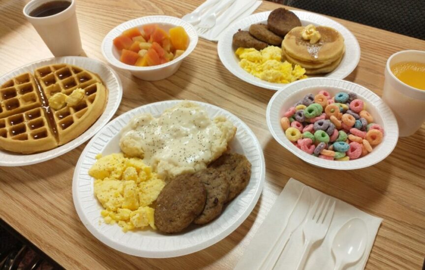 Breakfast plates with waffles, scrambled eggs, sausage, pancakes, fruit, cereal, coffee, and orange juice at The Dutton Inn | Branson Mo